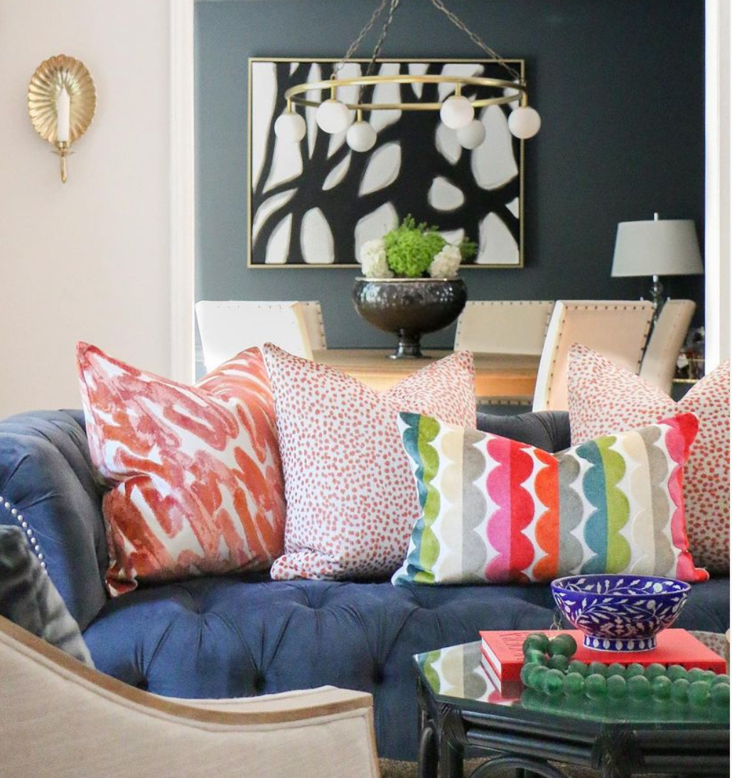 a mix of vibrant patterned high end decorative pillows on a bleu suede couch